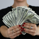 Ein Redaktionsfachmann mit einer Reihe von Banknoten in der Hand.